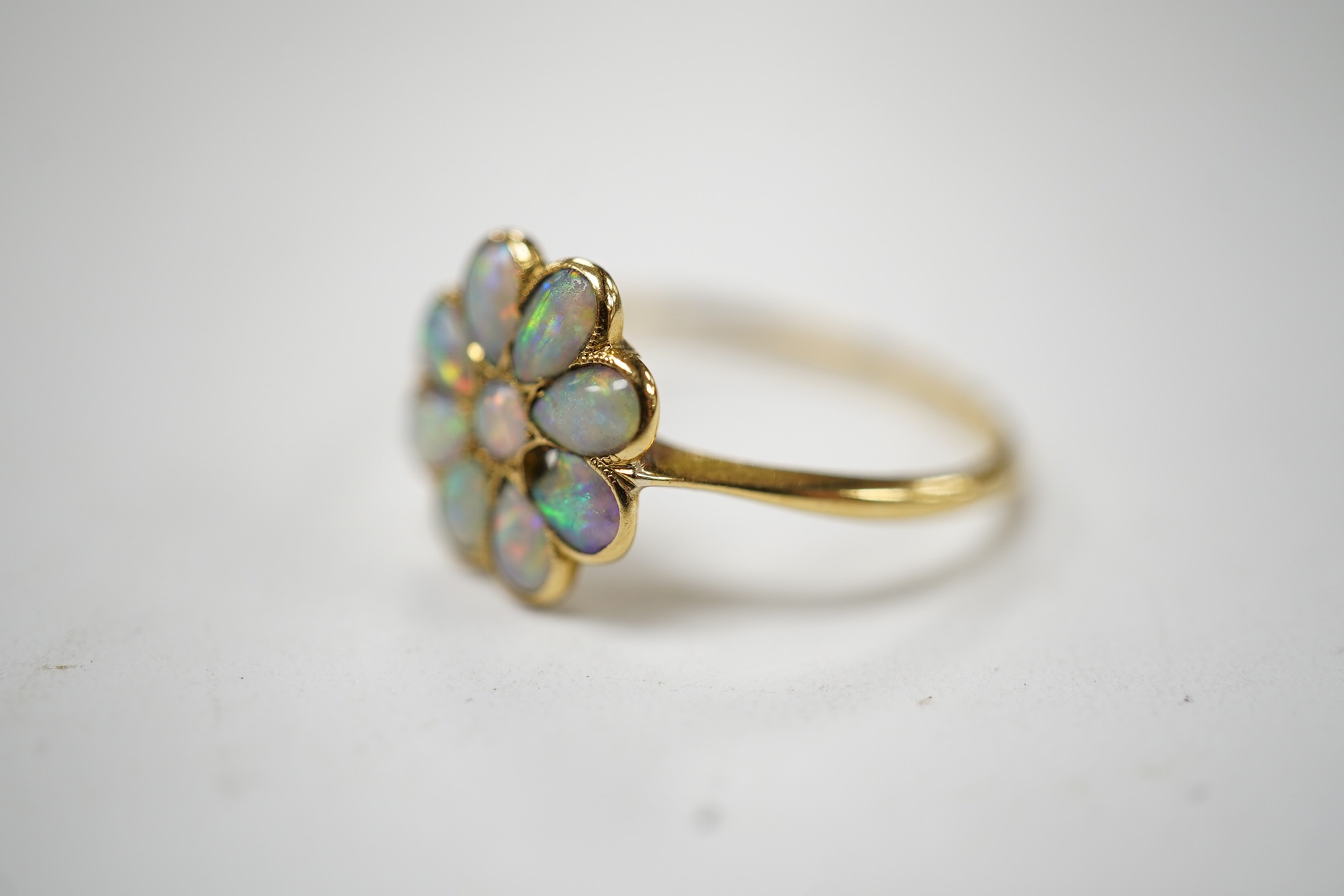 An 18ct and white opal set flower head cluster ring, size N, gross weight 1.7 grams. Condition - poor